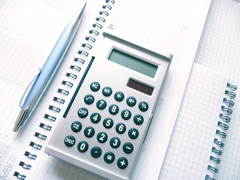 grey calculator laying on white papers will be used for calculating cost-efficiency